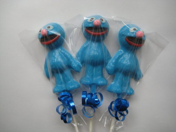 Three Grover character-shaped chocolate lollipops with red noses, wrapped in plastic and tied with blue ribbons.