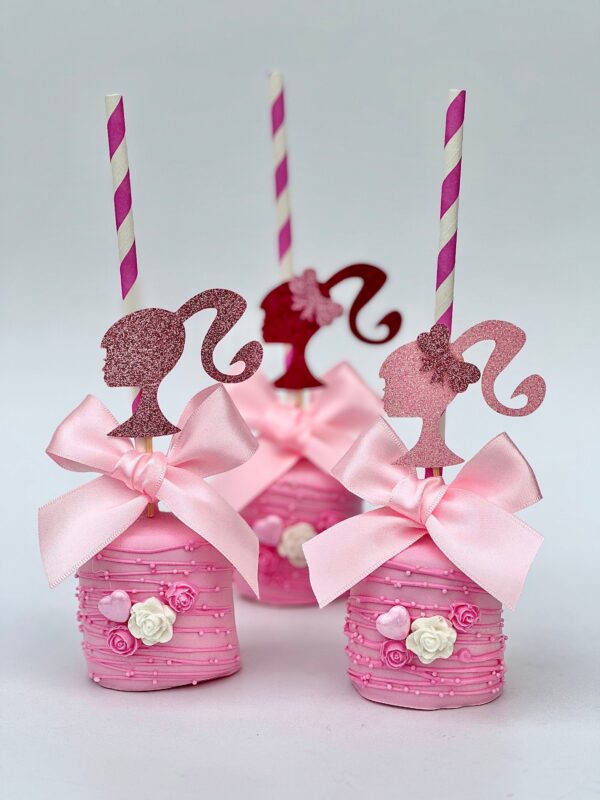 Three pink cake pops with bows, glittery toppers on striped straws, small roses, and white icing details match the theme of 12-Barbi Chocolate Covered Jumbo Marshmallows for a Barbi theme party.