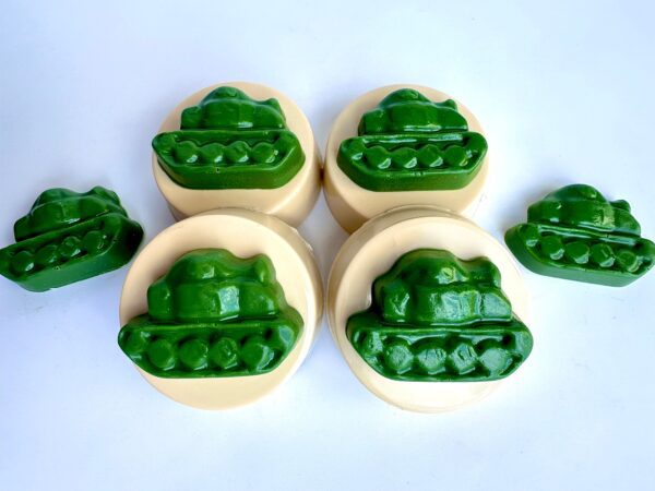 Green tank-shaped chocolate-covered Oreos on round beige bases, accompanied by two extra tank chocolates, set on a white background.