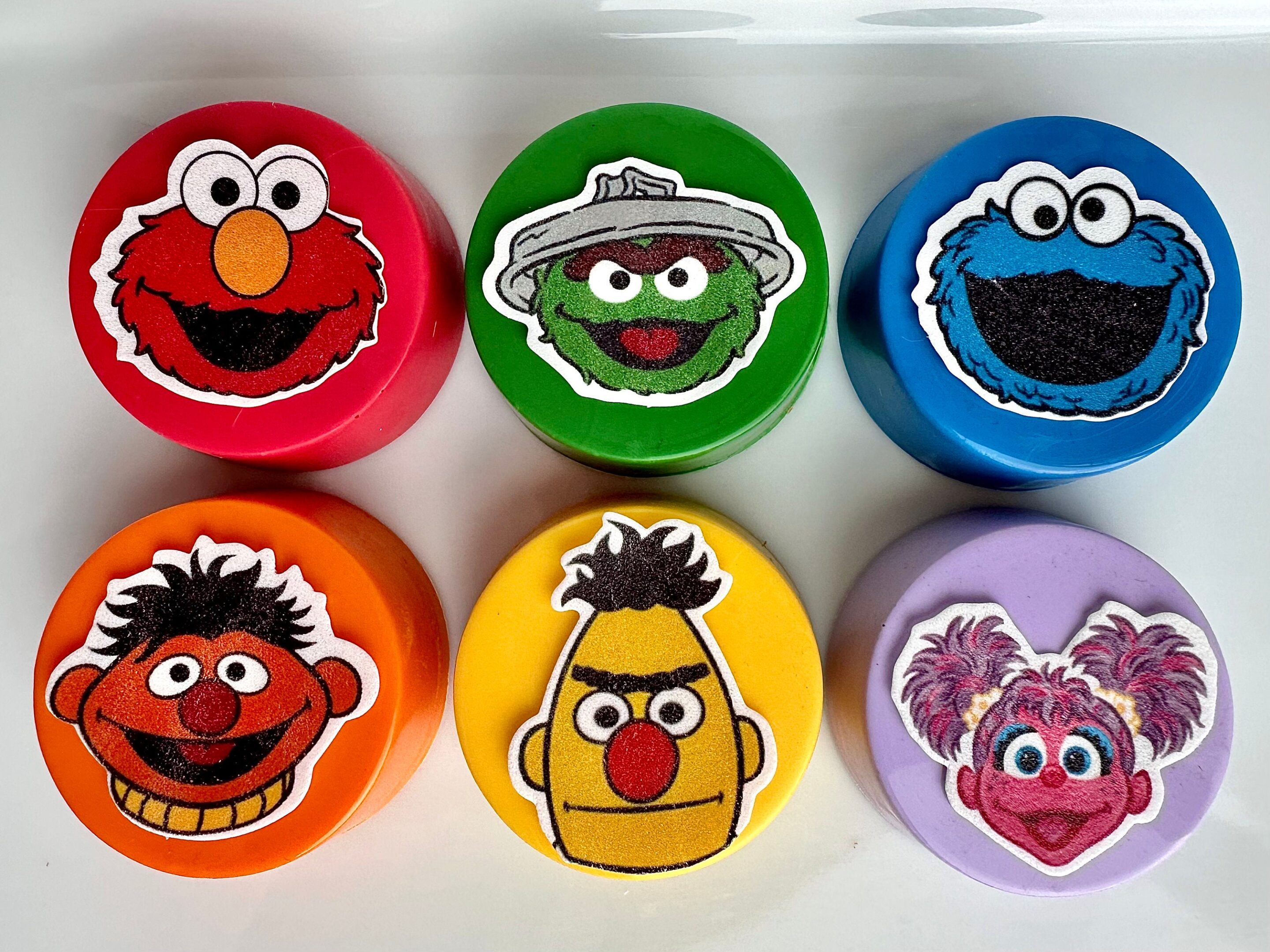 Six vibrant containers with cartoon faces in red, green, blue, orange, yellow, and purple: each features a unique character.