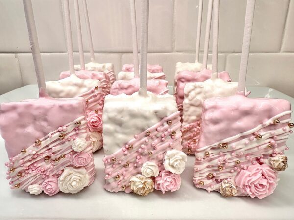 Pink and white chocolate treats on sticks, decorated with roses and pearls, arranged in rows, from the Pink and White Chocolate Treat Party Bundle for wedding or birthday favors.