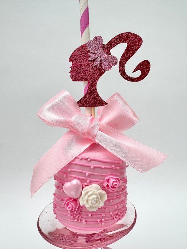 A pink jumbo marshmallow decorated with pink and white flowers, a bow, and a glittery silhouette of a woman's head on a striped stick, part of the 12-Barbi Chocolate Covered Jumbo Marshmallows collection for weddings, birthdays, or themed parties.