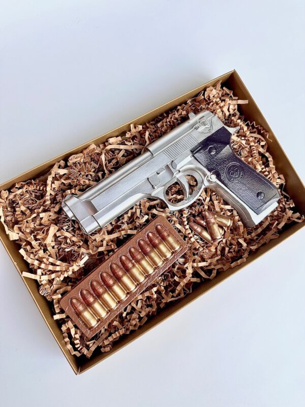 A Chocolate Hand Piece boxed gift for birthdays, dads, sons, or police officers includes a chocolate handgun and bullets in a gift box with shredded paper filling.