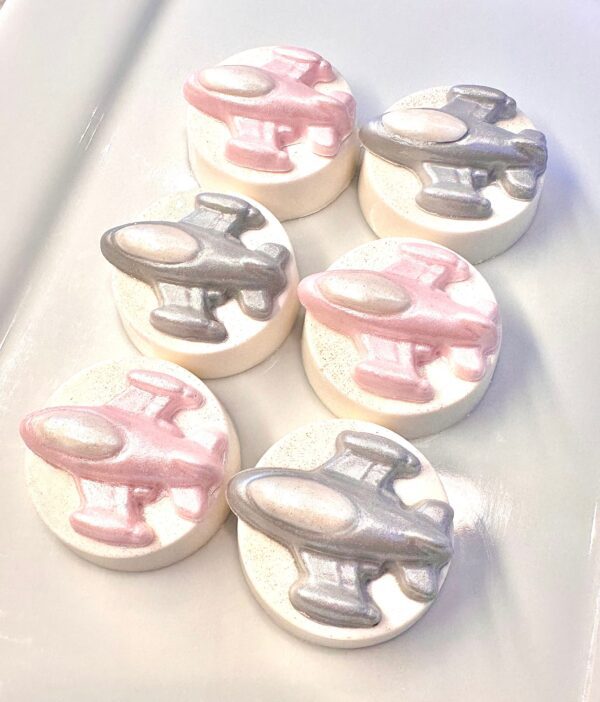 Chocolate-covered Oreos featuring airplane designs, with three pink and three silver planes, set on a white surface. Sold as "12-Spaceship Chocolate Covered Oreo Favors" for birthdays or space-themed parties.