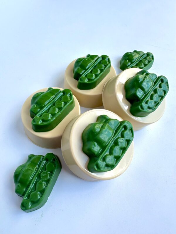 Green and beige 12-Tank chocolate-covered Oreo favors shaped like cucumbers are displayed on a white surface.