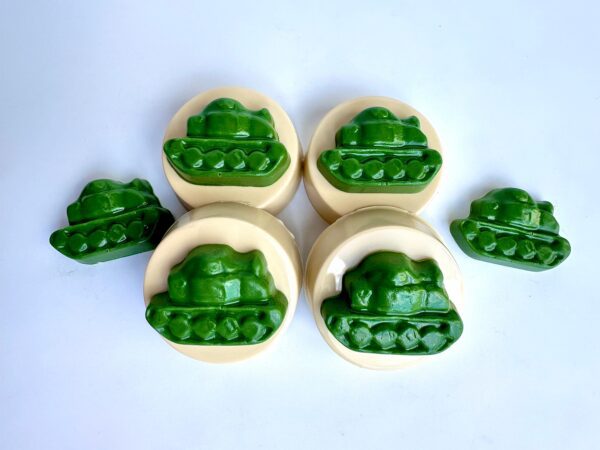 Five round chocolate-covered Oreo favors, each topped with a green tank-shaped figure, are arranged on a plain white background.