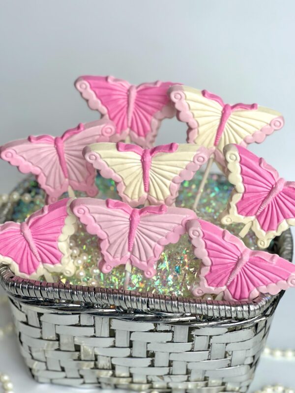 A silver basket filled with "12-Pretty in Pink" pink and white butterfly-shaped lollipops, adorned with shimmering decorative beads at the base.