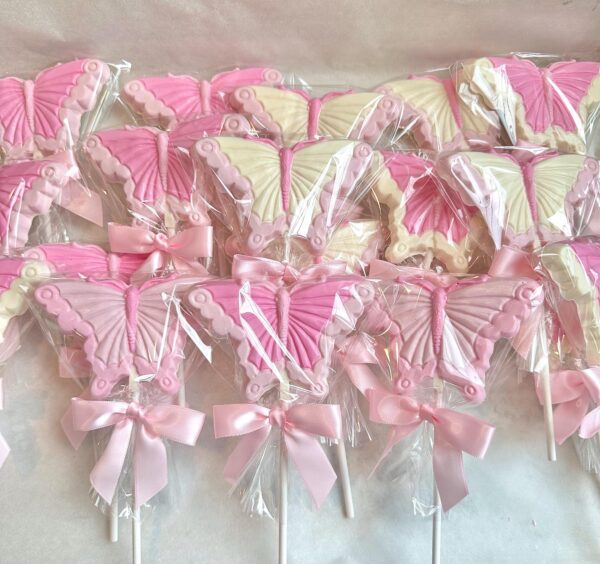 Pink and white butterfly-shaped lollipops, wrapped in clear plastic and adorned with a pink ribbon, from the "12-Pretty in Pink Butterfly Lollipops For Birthday Party/Shower Favors/Gift/Garden Party/Baby Girl" collection.