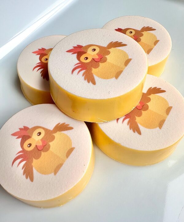 Five round Oreo favors with a baby chicken design, arranged on a white surface.