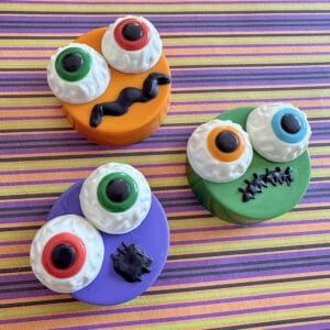 Colorful Halloween-themed decorated cookies on stripes.