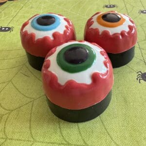 Three colorful eyeball-shaped soaps on table.
