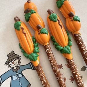 Pumpkin-decorated pretzel rods on scarecrow napkin.