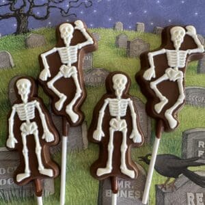 Skeleton-shaped chocolate lollipops on Halloween background.
