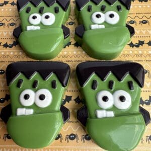 Green Frankenstein-themed cookies on Halloween paper.