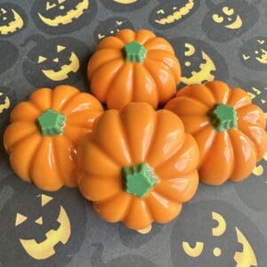 Four orange pumpkin soaps on Halloween background.