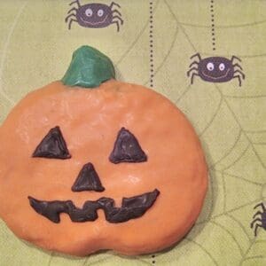 Pumpkin cookie on spiderweb-patterned background.