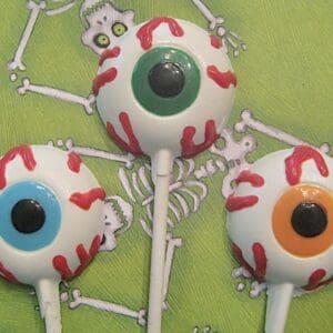 Eyeball lollipops on skeleton-patterned background.